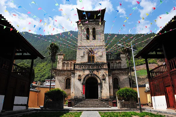 Stone Tibetan-style temple facade in Shangri-La courtyard, with colourful prayer flags strung overhead and arched entrance steps
