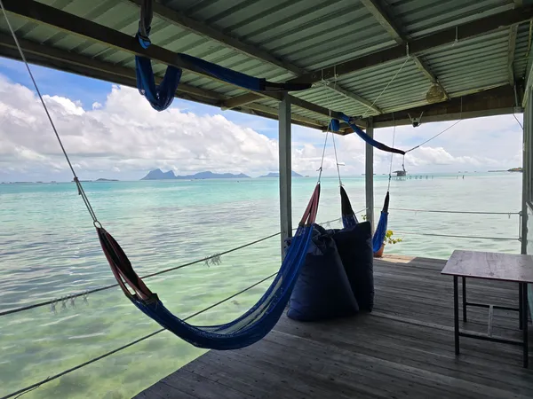 Hammock di dek banglo air di Semporna, menghadap laut yang tenang dan pulau-pulau di kejauhan semasa menginap bersama Bigfin Divers
