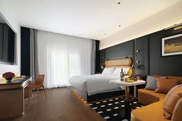 The Bivou Lijiang suite with a white bed, dark walls and seating by the window at Shuhe Ancient Town, Lijiang