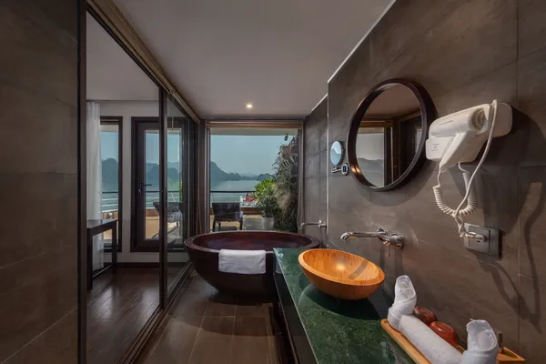 Oval mirror and stone tub in the bathroom, with Halong Bay water and karst scenery seen through the cruise windows on Oasis Bay