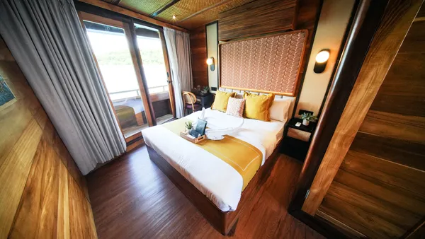 Angelica Liveaboard cabin on a 3D2N luxe Komodo cruise with a made-up double bed and wood-panelled walls in Labuan Bajo