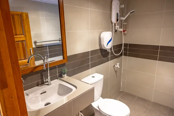 Modern en-suite bathroom with white basin, mirror, toilet and shower fixtures on Seaventures Dive Rig offshore stay in Semporna