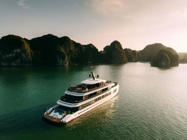 Sunshine Golden Cruises luxury cruise boat at sunset on calm bay water between limestone karsts on a 2D1N cruise — Cat Ba