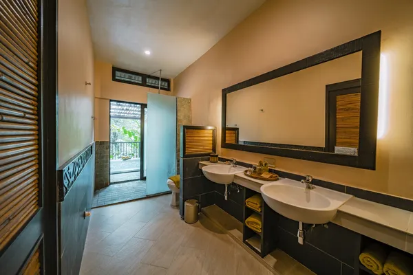 Borneo Rainforest Lodge suite bathroom with double sinks, large mirror and shower doorway, set in Danum Valley