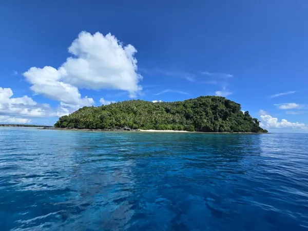 Laut biru dengan pulau tropika yang menghijau berhampiran terumbu kepulauan Semporna, ketika perjalanan selam skuba bersama Bigfin Divers di Sabah