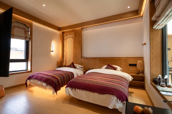 Shangri-La twin bedroom with two beds made up in striped duvets, warm lighting, and wooden furniture in a cosy guest room