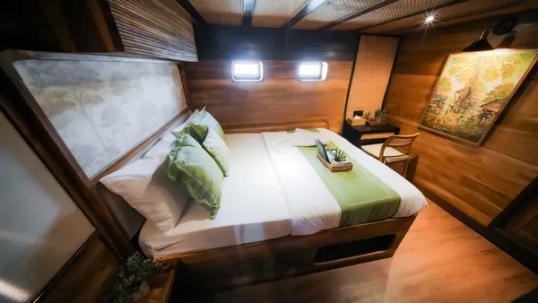 Luxe phinisi cabin bed with green cushions for the 3D2N Komodo cruise, sunset BBQ and jacuzzi in Labuan Bajo