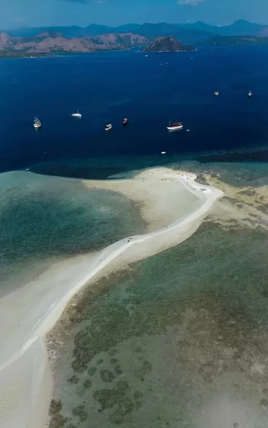 Aerial coastline view with calm bay water, boats anchored in shallow sea, and a sweeping sandbank on a Rare 3D2N trip, Komodo Island