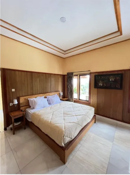Double bed in a tidy hotel room with wooden panelling and a window, included with the 2D1N sunrise trip to Mt Bromo