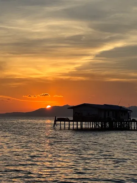Sunset at a stilted sea lodge in Semporna, with wooden overwater buildings and calm bay water at golden hour