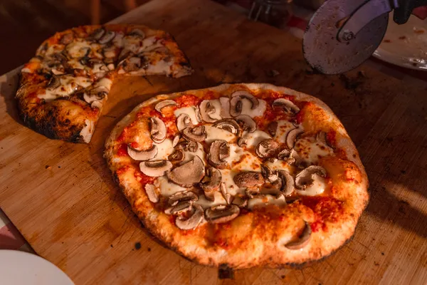 Mushroom-topped wood-fired pizza on a wooden board at a cosy table, served as part of a private dining Singapore meal