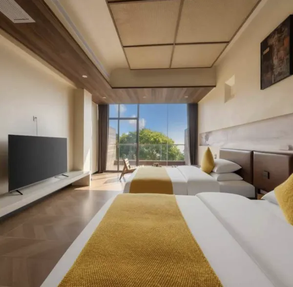 Bright suite room in Xishuangbanna tea lodge, with sliding glass doors, two beds, and neutral modern furnishings