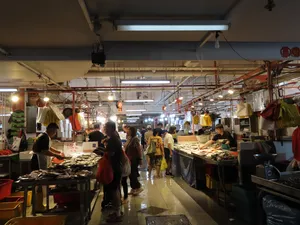 Bustling seafood market aisle in Singapore with hawker stalls and shoppers, showing how Cantonese fish is sourced on a tour