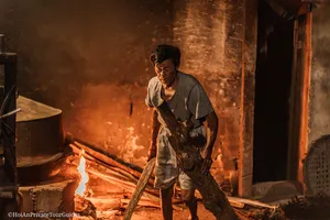 Ha carrying firewood through a lantern-lit doorway in Hoi An, showing everyday trades on an early-morning tour