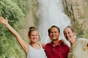 Smiling travellers posing at a waterfall in Khao Yai National Park during the wildlife trek experience