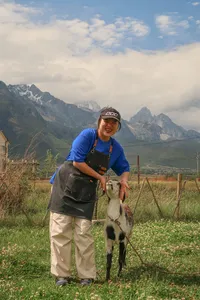Coffee farming on a mountain farm in Lijiang with Seeker Yunnan Coffee Estate: a host feeds a goat with hills behind