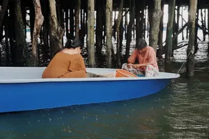 Small boat gliding through rows of wooden stakes in Johor Bahru during a nature-educator private coastal tour