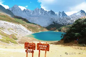 Turquoise alpine lake and glaciers beyond red signposts in Shangri-La, framed by rugged snow peaks on a mountain walk