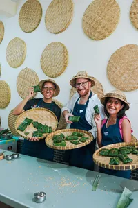 Small group in aprons and hats during a Bali tempe making workshop, holding woven trays with leaf-wrapped tempe
