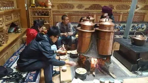 Copper cooking pots and an open flame over a stove during a Tibetan home lunch in Shangri-La, in the family kitchen