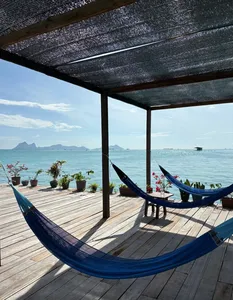 Buaian hammock di dek terbuka banglo air di Semporna, menghadap laut dan bukit di kejauhan semasa menginap di Bigfin Divers