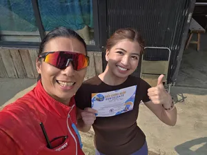 Two paragliding participants smiling and holding a flight certificate at the launch area, ready to fly in Sapa