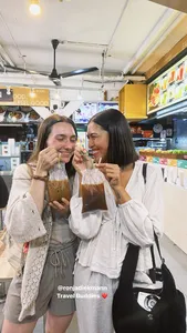 Two travellers smiling and sipping drinks inside an eatery during a private night walk in Geylang, Singapore — Singapore hidden gems