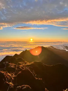 Golden sunrise from a mountain ridge above Sapa, with winding paths and ridgeline haze glowing at Mt Fansipan