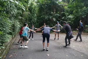 Team trekking along a paved path through tropical rainforest on a Fort Serapong discovery adventure in Singapore