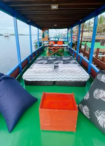 Boat cabin on a Sister Tour Tanjung Puting small-boat cruise, with cushioned berths and a chest on the green floor