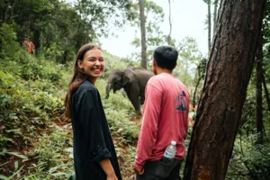 Smiling travellers meeting an elephant in a rainforest clearing on the Hidden Doi Inthanon trails near Chiang Mai