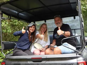 Three visitors smiling and giving thumbs-up inside an open safari jeep on the way through Khao Yai National Park forest