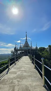 Sunlit concrete viewpoint walkway beside Buddhist pagoda towers overlooking jungle canopy in Khao Sok National Park