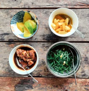 Bowl of fruit, leafy greens and soup plated on a wooden table at Ngapuh Homesteadβs regenerative homestead near Kuching