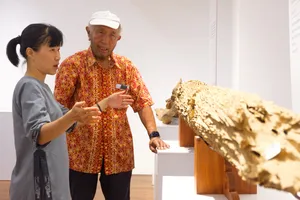 Guide and visitor examining a large agarwood log display inside a Hanoi venue on an Up Travel Vietnam rare agarwood tour