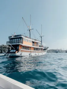 Deluxe phinisi sailing on open water with other boats in the distance during a 4D3N shared Komodo cruise, Labuan Bajo
