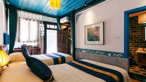 Bilik tidur warisan dengan kemasan biru di Linden Centre, Pekan Lama Xizhou, Dali, dengan katil double dan lampu sisi katil yang lembut