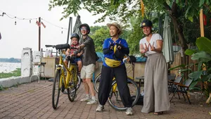 Cyclists posing with yellow bicycles at a riverside pier on Mekong Island near Ho Chi Minh City on a Jackfruit Adventure tour