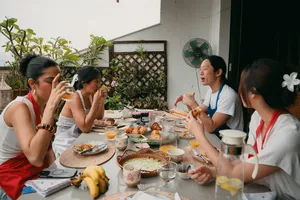 Croissant baking class in a Singapore home: guests around a shared table with drinks and pastries while the French chef guides