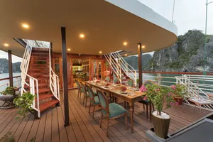Alfresco dining deck on Cat Ba Ocean Cruises, with set tables and chairs overlooking Lan Ha Bay and limestone cliffs