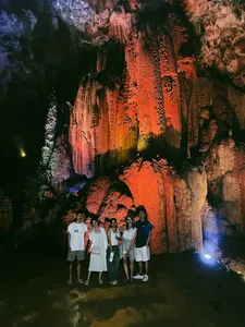 Group of travellers standing under dramatic cave lighting with a rocky ceiling during the Cao Bang motorbike adventure