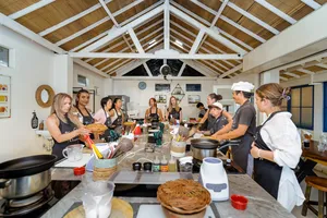 Small group Indonesian cooking class on Gili T in Lombok gathered around pots and utensils under a high white ceiling