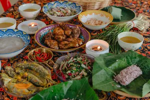 Kota Kinabalu Indigenous Sabahan cooking feast spread with grilled meat, herbs and steaming bowls on a patterned table
