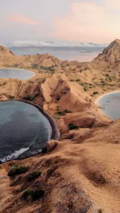 Aerial view of dry hills and winding coastal inlets at sunset from a deluxe phinisi cruise near Labuan Bajo