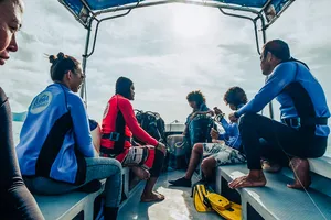 Divers seated on the deck of a dive boat in Semporna, ready with snorkelling and diving gear for a 2D1N stay