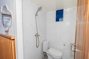 On-board bathroom on the La Famille Komodo boat with marble-look shower, handheld spray and toilet, ready for guests in Labuan Bajo