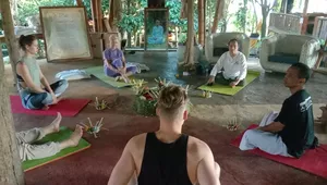 Participants seated cross-legged on bright mats with flower offerings during a guided meditation session at Omunity Bali in Bali
