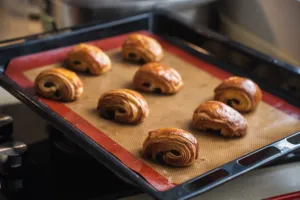Golden croissants arranged on a parchment-lined baking tray in a Singapore oven, ready for workshops in Singapore