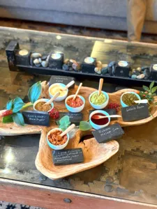 Mangkuk cecah dan sos daripada tumbuhan yang boleh dimakan dengan label kapur di atas papan kayu, disediakan untuk pengalaman membuat roti hidden gems di Singapura