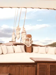 Komodo Island phinisi deck lounge with cushioned seating and hanging life jackets, part of a Travass Life 3D2N shared trip